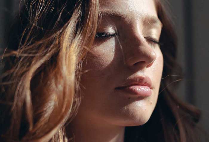 Young face woman at sunlight with curly hair fashion model with closed eyes female girl cosmetic beauty portrait confident happy cheerful enjoy relax close up